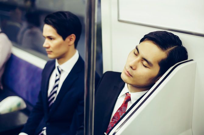 日本の地下鉄車内で居眠りする人
