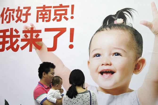 中国東部の江蘇省南京市で開催された展示会で、広告を見る家族＝2014年9月13日