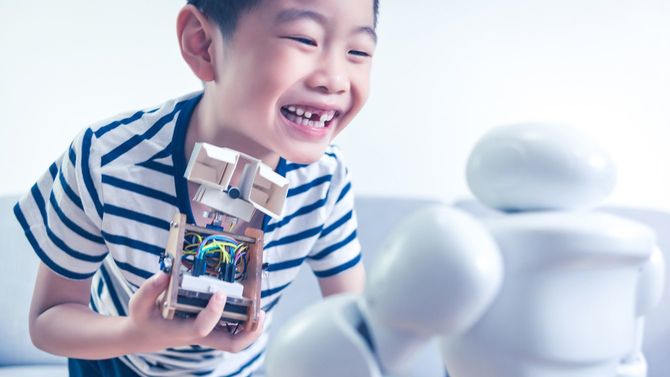 小さな科学者が自分で作ったロボットをロボットに見せている