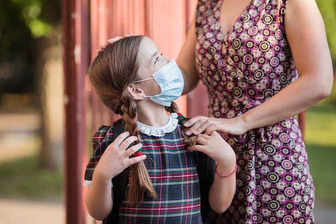 学校が始まる前に母親にさよならを言うかわいい学校の女の子