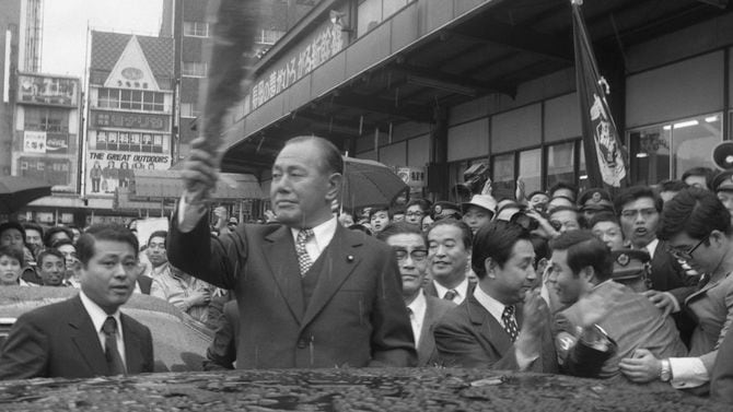 6カ月ぶりの郷土入りで、贈られた花束を手に出迎えの人たちに応える田中角栄前首相（新潟・長岡市の国鉄長岡駅前）