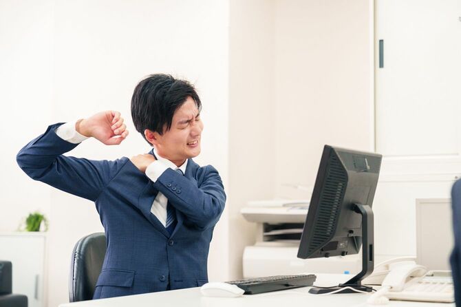 オフィスで肩こりをほぐすビジネスパーソン
