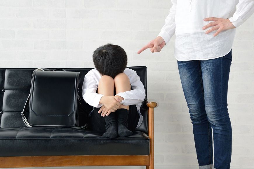 親に叱られてソファにうずくまる子供