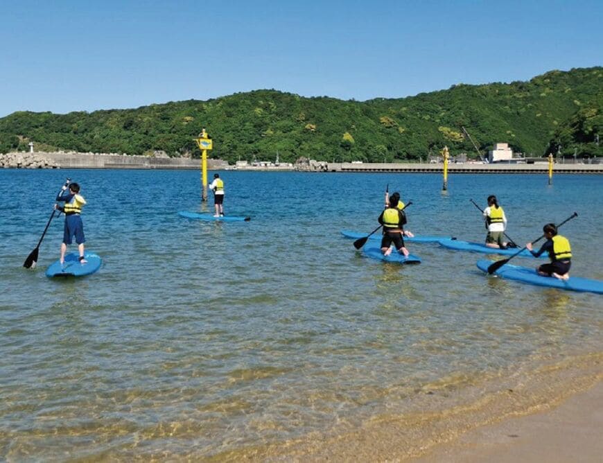 和歌山県すさみ町で行うフレッシャーズキャンプの一コマ。美しい海でSUPを体験。