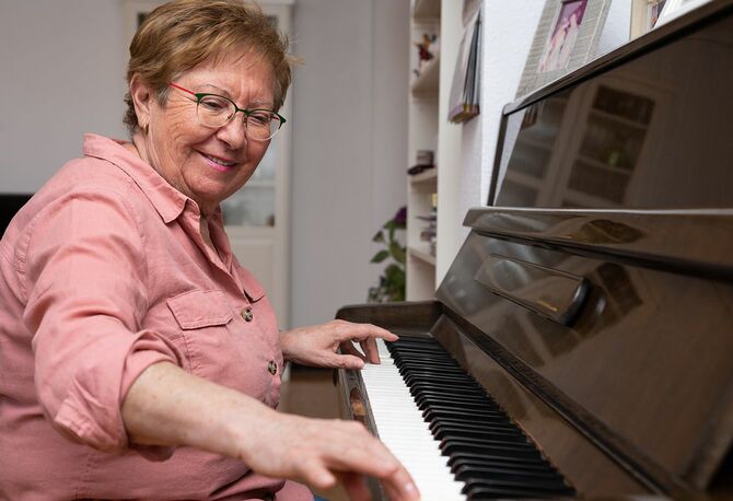 家でピアノを弾く笑顔の年配の女性