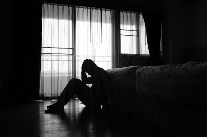 寝室に座るうつ病の男性のシルエット