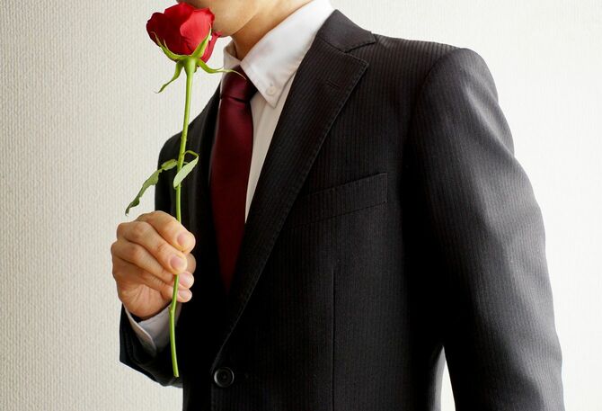赤いバラの花を持つビジネスマン
