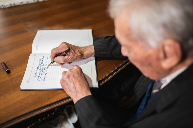 ペンで紙に何かを書き留める年配の男性