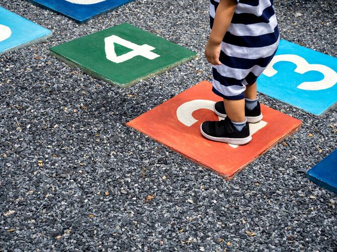 色とりどりのホップスコッチで2番地に立っている小さな男の子