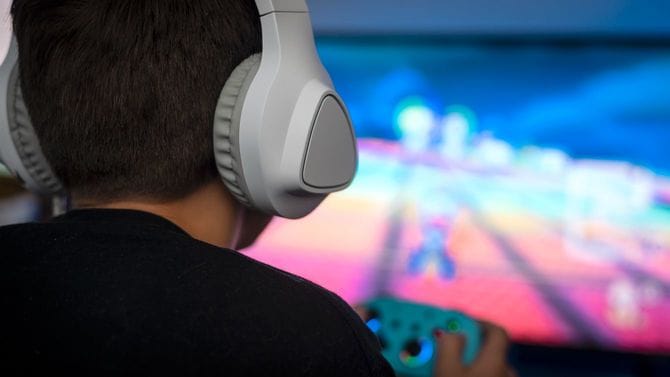 部屋でヘッドフォンをつけてビデオゲームをしている男の子