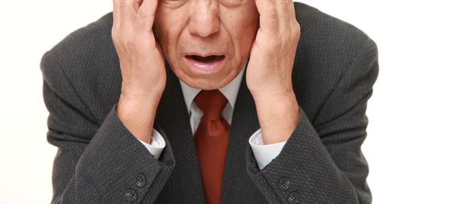 こめかみを押すシニア男性