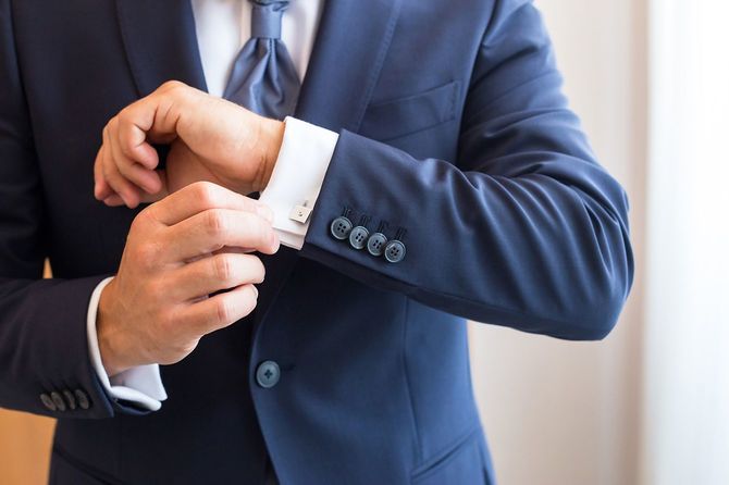 白いシャツのカフを留める男