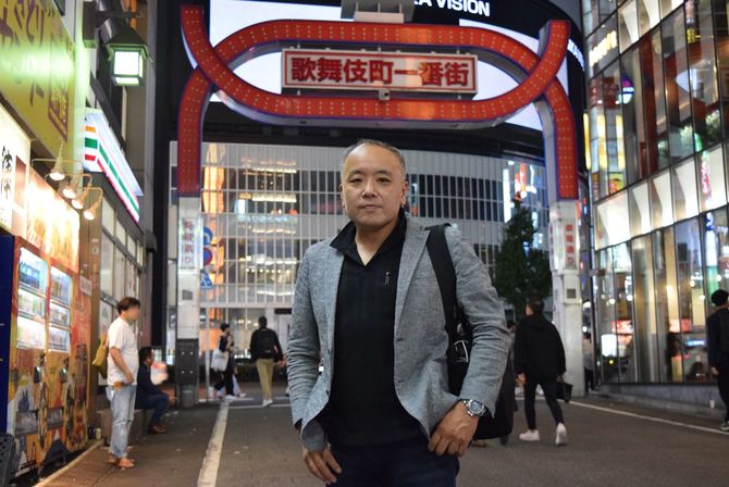 「歌舞伎町一番街」のアーケード前に立つNPO法人「レスキュー・ハブ」代表の坂本新さん