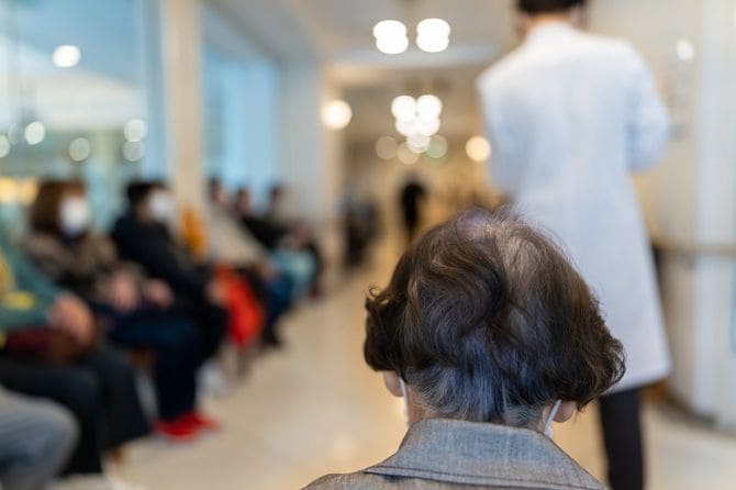 満員の病院の待合室にいるシニア女性