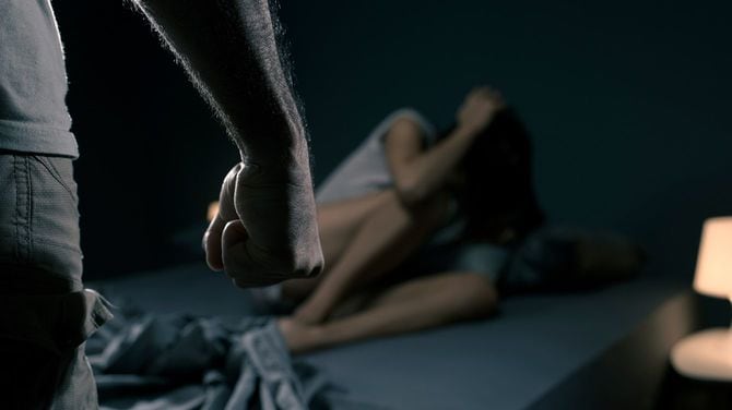 おびえて身を屈める女性の手前に、男性の握りこぶし