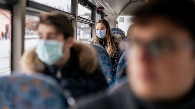 マスクを着用してバスに乗る若い女性