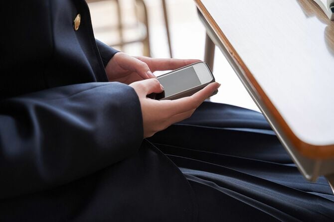 隠れて携帯電話を操作する中学生の女の子