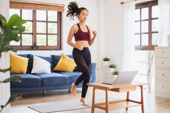 自宅の部屋でその場でジョギングをする女性