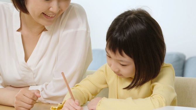 自宅で母親と一緒に勉強している子ども