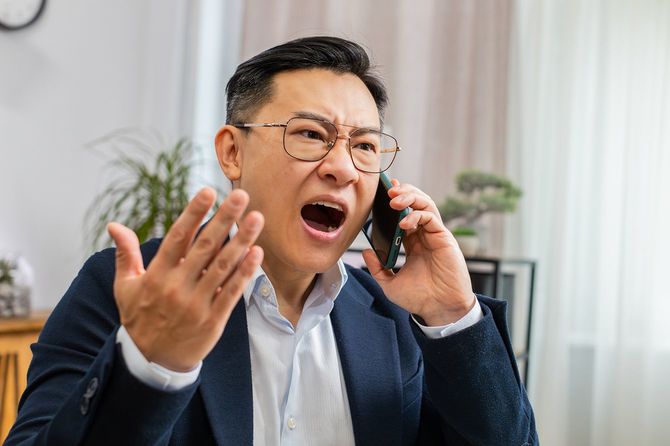 怒ったビジネスパーソンがスマホ通話