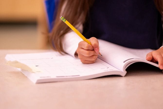 演習帳に鉛筆で回答を書き込もうとしているちいさな手