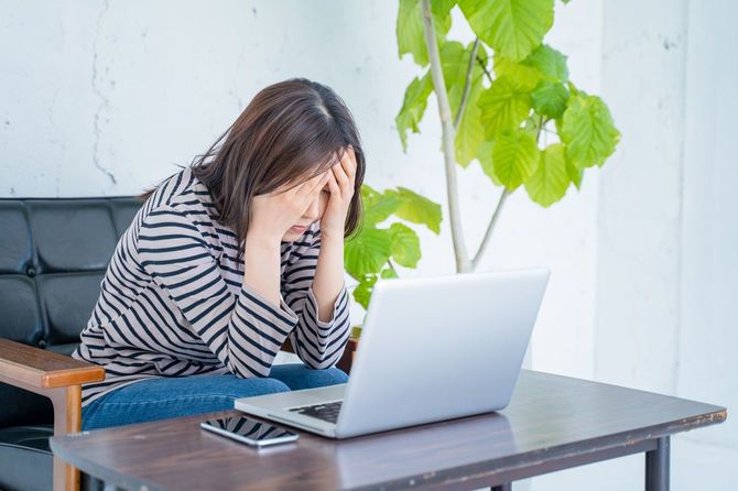 リビングルームで、ノートパソコンを前に頭を抱えている女性