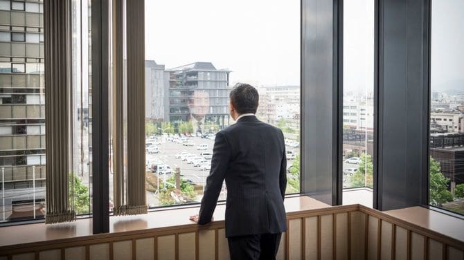 窓から外を眺めるビジネスマン