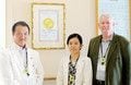 亀田隆明理事長とJCI認証取得に取り組んだジョン・C・ウォーカー氏と佐野元子さん。
