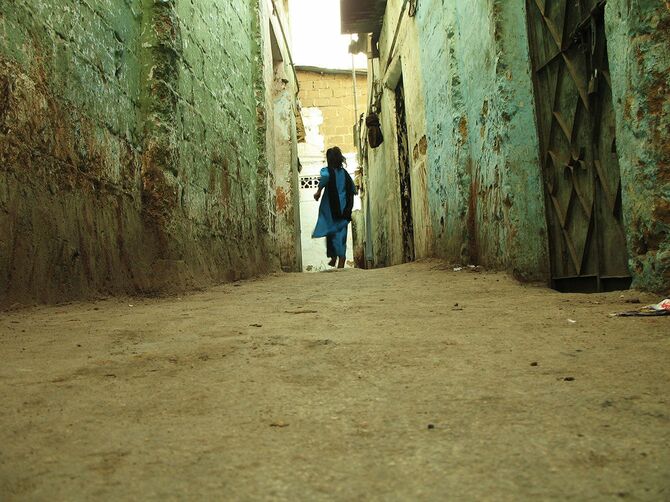 インドの狭い路地を駆け抜ける女性