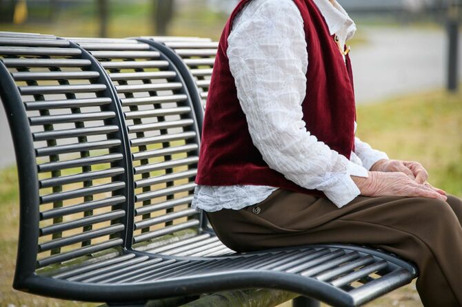 公園のベンチに座るシニア女性