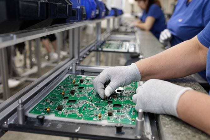 最新のSMT生産ラインでPCBを組み立てる手袋をはめた技術者の手元