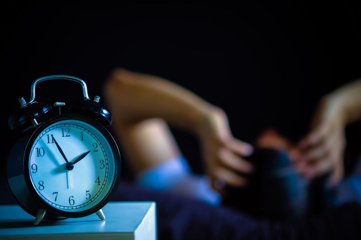 不眠に悩む男性、時計は深夜1時56分を指している
