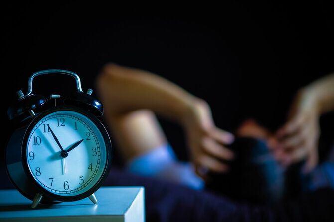 不眠に悩む男性、時計は深夜1時56分を指している