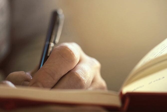 ペンを持って書く人の手
