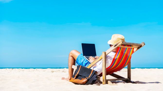 熱帯のビーチでラップトップを使用している男性