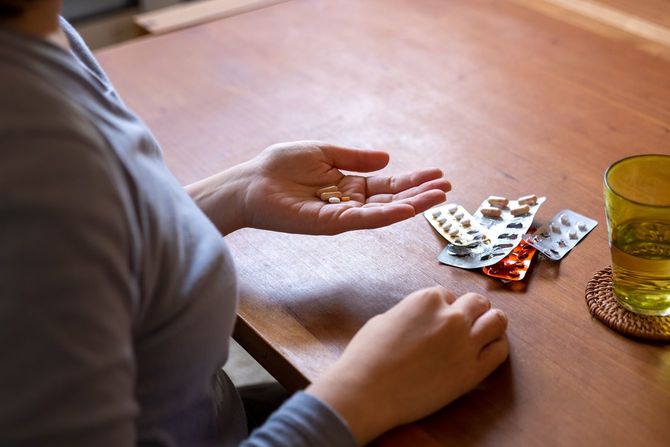 自宅の部屋で薬を飲んでいる女性