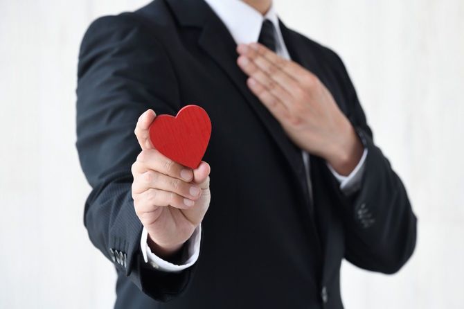胸に手をあてハート型のオブジェを持つビジネスマン