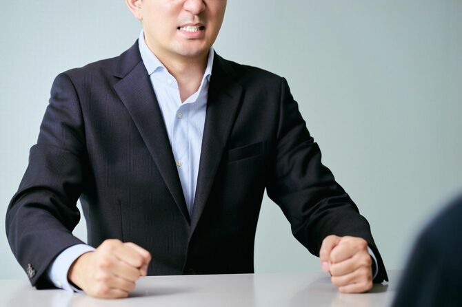 手で机を叩き怒りをあらわにするビジネスマン