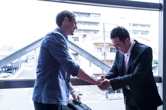 笑顔で握手し礼をするビジネスマン