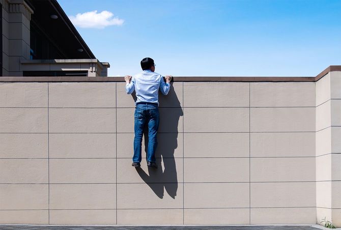 コンクリートの壁を乗り越えようとする男性