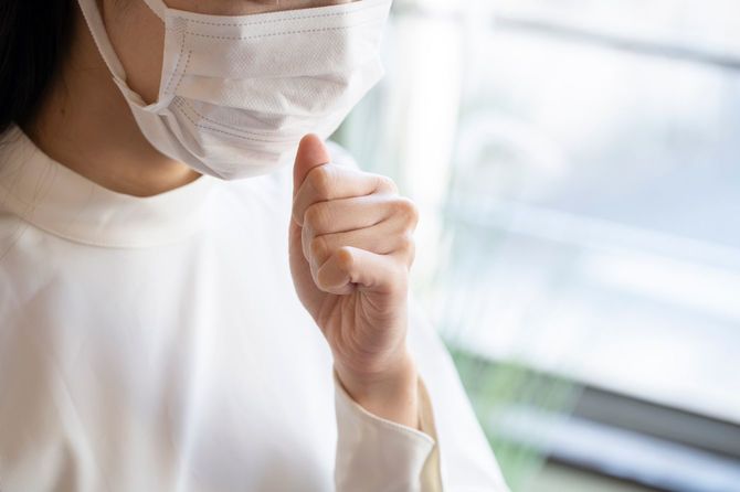 マスクをして咳をする女性