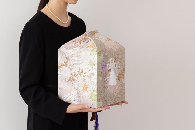 骨壺を持つ喪服の女性