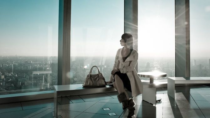 モダンな高層ビルのベンチに座る女性