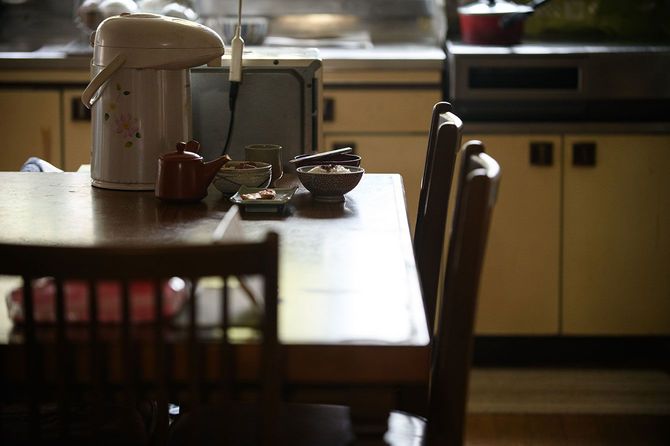 一人分の食事が置かれたテーブルがある、古い家の台所