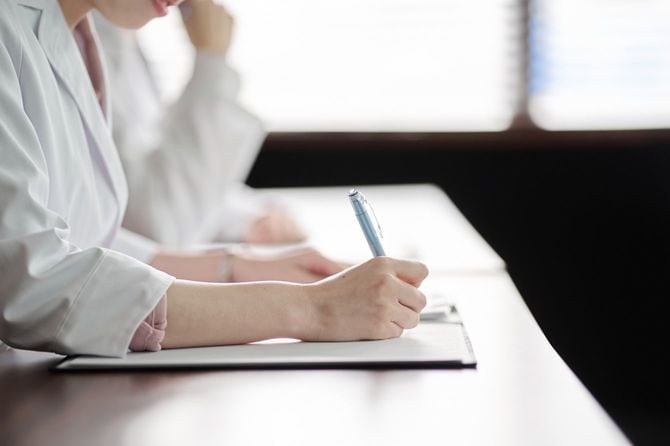 セミナーに出席する白衣を着た人の手