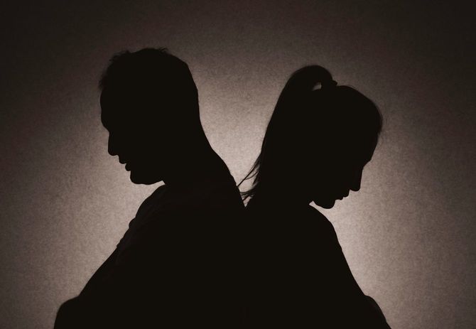 背中合わせでうつむく、難しい関係のカップル