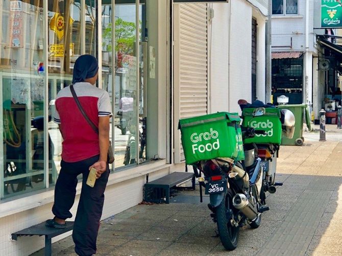飲食店の前で宅配の料理ができるのを待つ飲食宅配代行ドライバー。飲食店は原則閉鎖が求められているなか宅配注文が殺到している