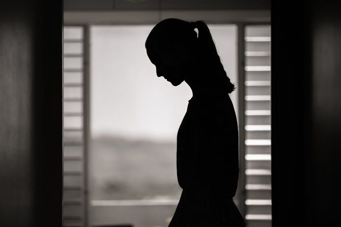 暗い室内で悲しみに暮れている女性のシルエット