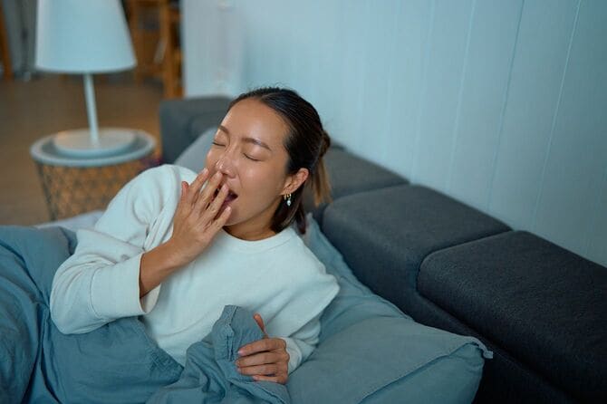 眠気を感じながらあくびをする疲れた女性