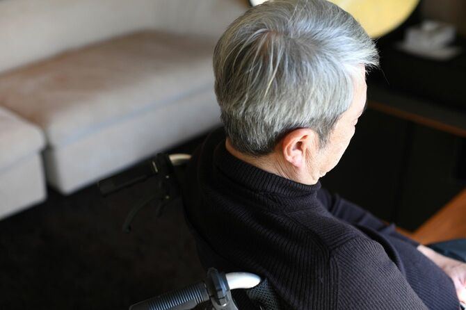 車椅子に一人で座っている白髪のアジア系老人の後ろ姿